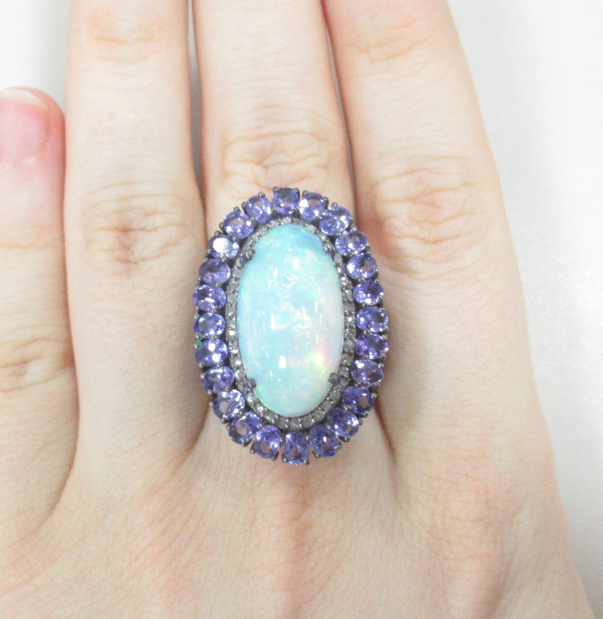 Серебряное кольцо 925 пробы; родий (бел.черн.); вставки 1 Опал бел. 10,5ct (Эфиопия); 24 Танзанит 4,04ct; 40 Бр.Кр-17 0,31ct 3/5;